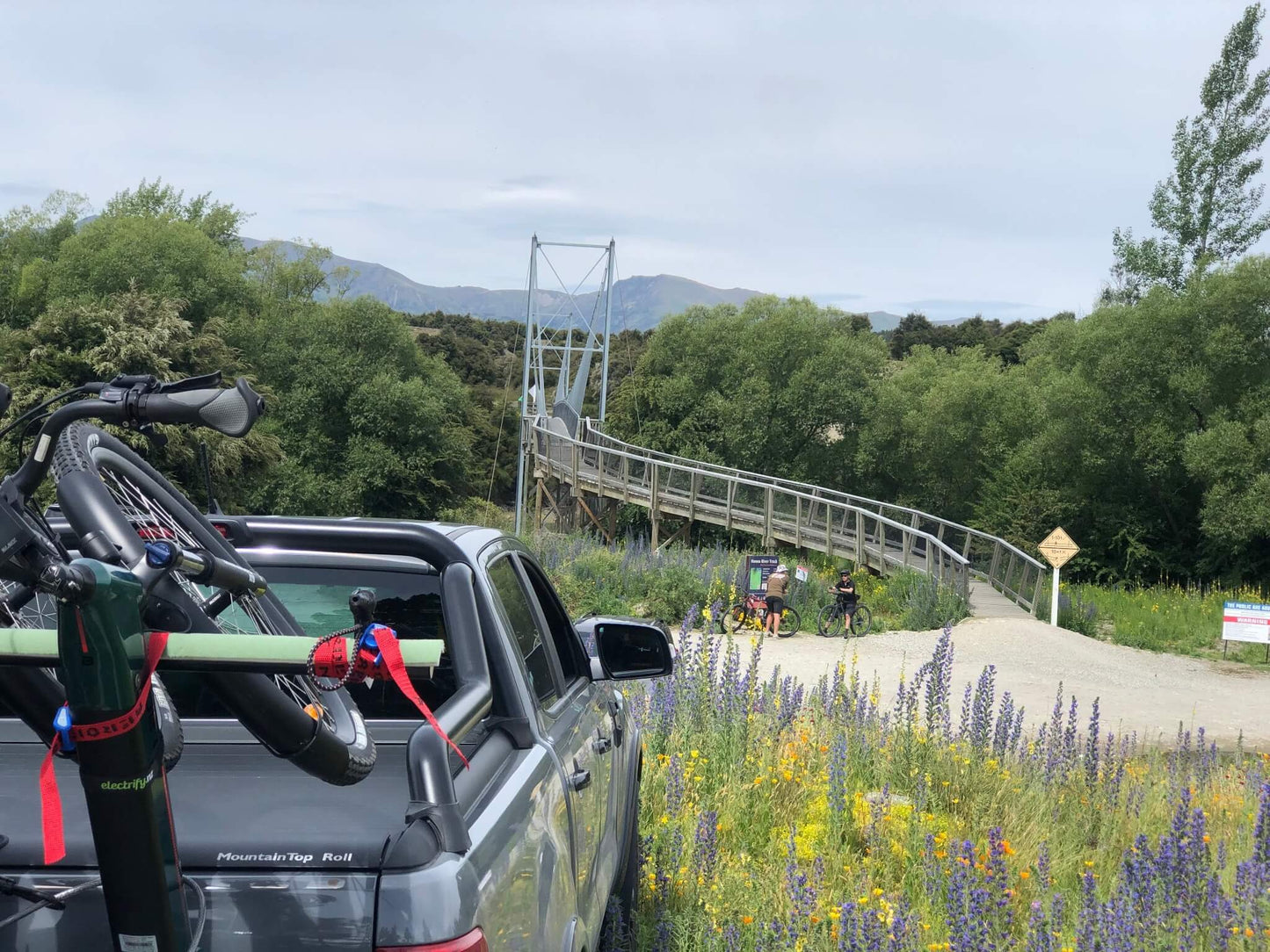 Truck with bike near Hawea bridge and cyclists on trail