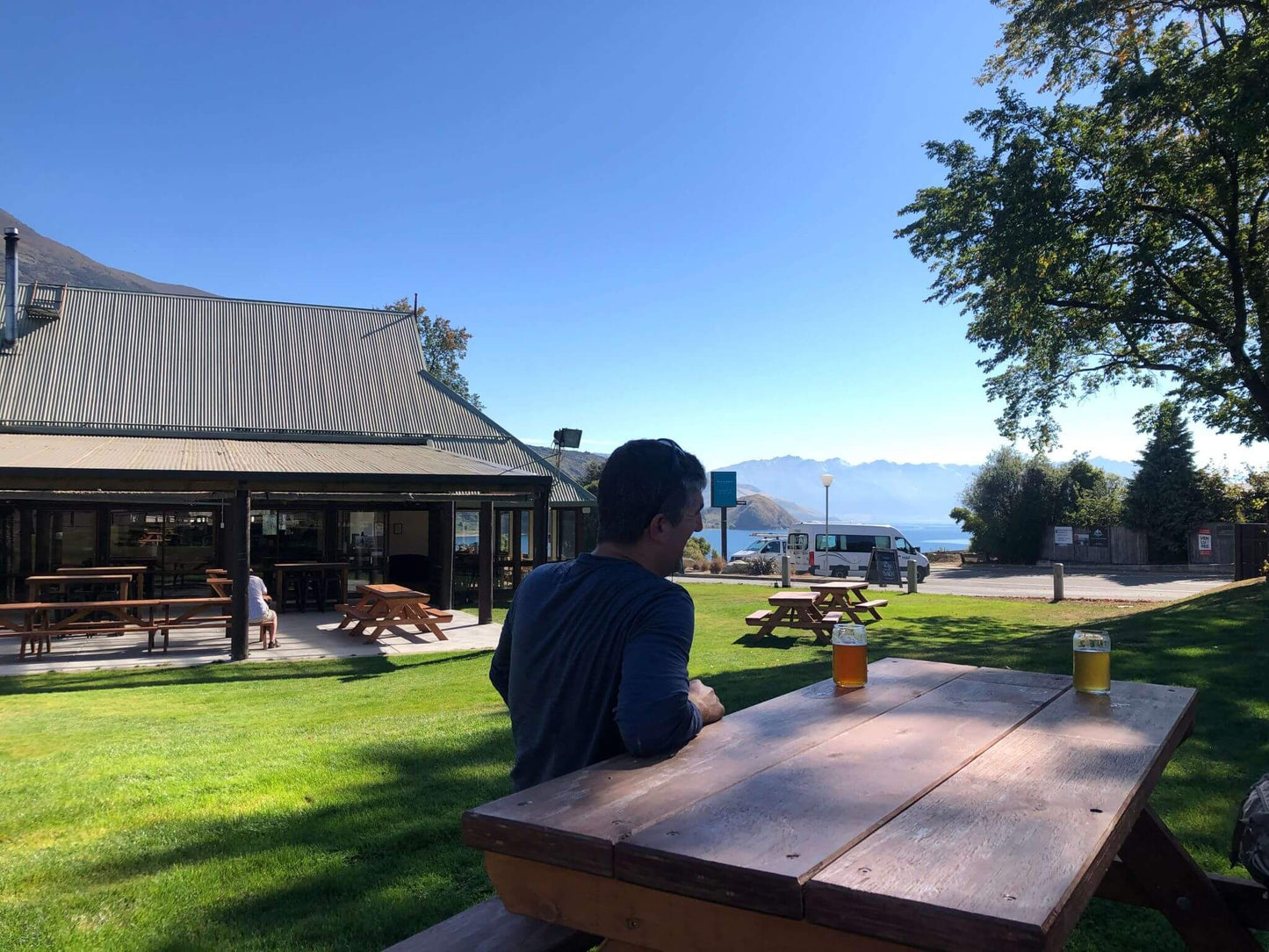 Man sitting at outdoor picnic table with craft beers