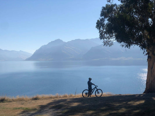 Cyclist with e-bike standing by Lake Wanaka